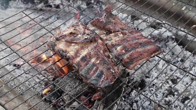 Costillas en la parrilla con fuego debajo de la parrilla.