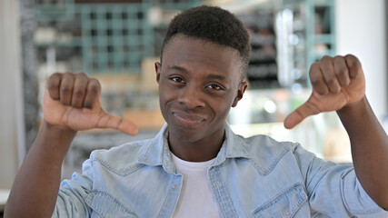 Naklejka premium Portrait of Disappointed Young African Man doing Thumbs Down