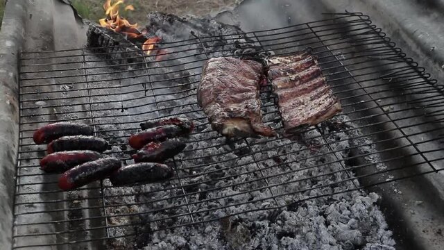 Chorizo y costillas sobre una parrilla sobre fuego.