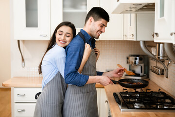 Loving couple preparing dinner frying meat on pan