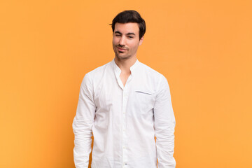 young handsome man looking happy and friendly, smiling and winking an eye at you with a positive...