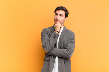 young handsome man feeling thoughtful, wondering or imagining ideas, daydreaming and looking up to...