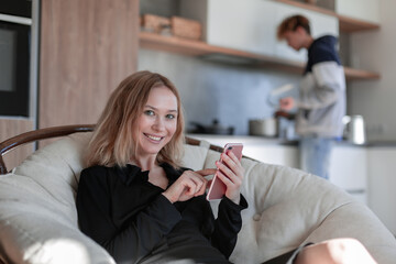 Smiling woman with phone at the kitchen