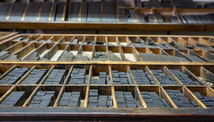 Letterpress letters placed in printing cabinet, old printing press. Ancient trade, focus selective