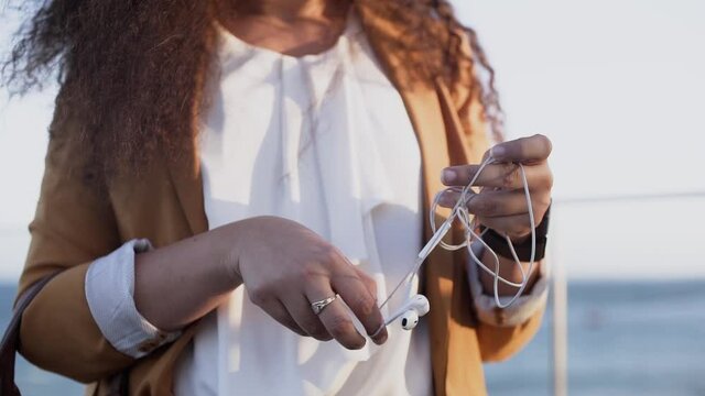 Close-up of young woman's hands untangling tangled earphones