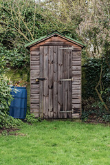 Old wooden traditional garden shed in an overgrown area shot front on.