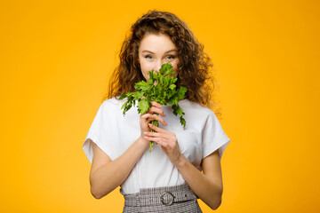 Pretty caucasian girl with curly hair holding green parsley