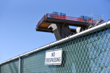 No trespassing sign at construction site with pillar for bridge in progress in background