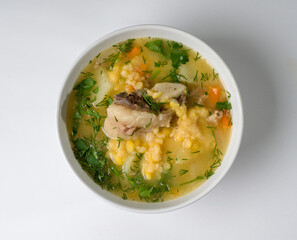 Pea soup with meat in a white bowl. Peas, meat, potatoes and greens