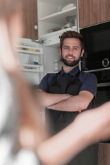 Smiling attractive young man standing near refrigerator