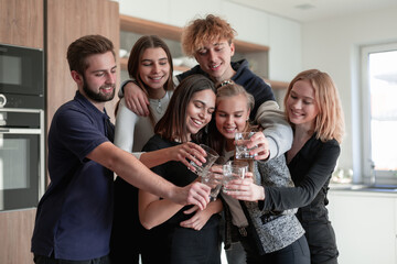 Group of smiling friends having drinks in the kitchen