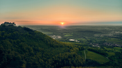 Aerial view of a sunset in Germany over green landscape with small villages.  In the left half of...