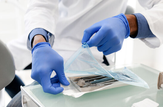 Black dentist hands opening sealed set of dental tools