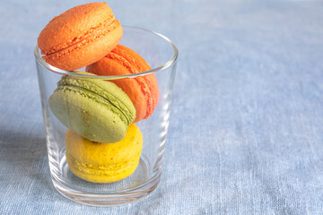 Multi-colored macaroons in a glass cup on a linen napkin. Mcarons or macaroons is French or Italian dessert. Copy space