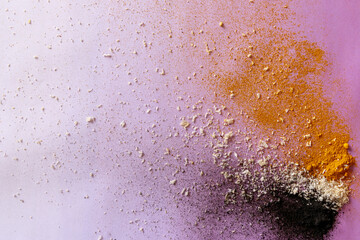 Violet background with colorful explosion of ingredients - activated carbon, coconut and turmeric