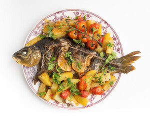 Dish of carp fish grilled with potato and tomatoes