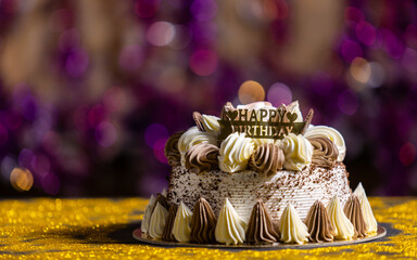 Happy birthday cake with candles, bright lights bokeh.