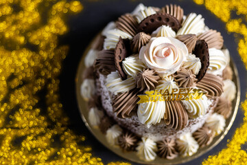 Happy birthday cake with candles, bright lights bokeh.
