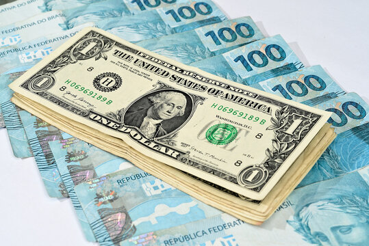 Notas de 1 dólar junto com notas de cem reais brasileiros 