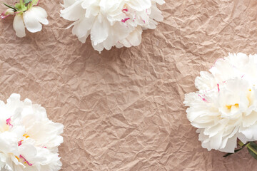 Flower composition made of white peonies on crumpled craft paper. Women's Day, Mother's Day, wedding, spring or summer rustic floral background. Flat lay, top view, copy space.