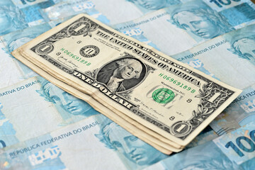 Notas de 1 dólar junto com notas de cem reais brasileiros 