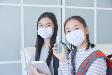 Young asian schoolgirls wearing facial mask and using alcohol spray at school for prevention covid-19 infection.