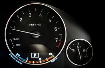 Close up of Analog Car dashboard with Tachometer RPM meter and Engine oil temp gauge on background