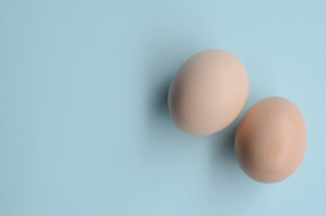 Two chicken white eggs on the blue background with empty space
