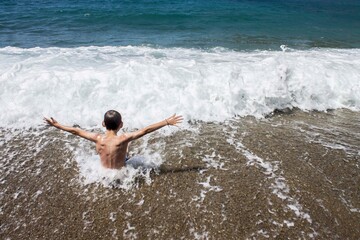 Fototapeta premium Niño disfrutando en una playa, mar y arena