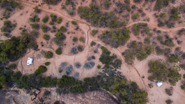 Vertical drone view of a 4WD and a caravan in  at a free camp near a granite outcrop in the Australian outback.