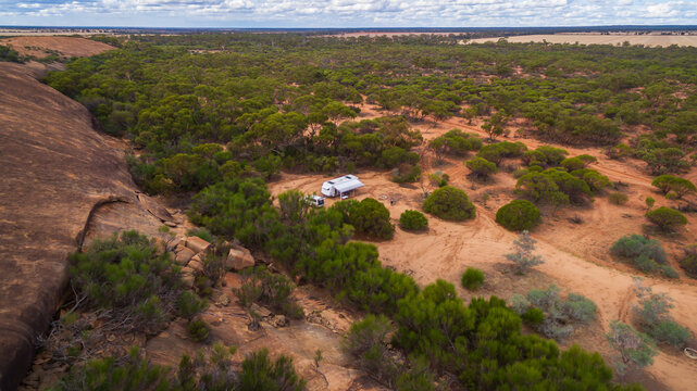 Oblique drone view of a 4WD and a caravan in  at a free camp near a granite outcrop in the Australian outback.