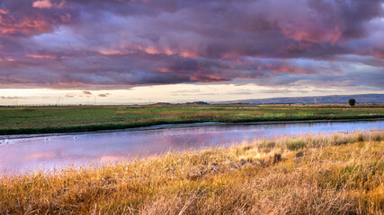 Dramatic sunset landscape with storm clouds reflected in the restored wetlands of South San Francisco Bay Area; Mountain View, California