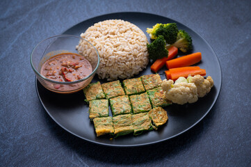 khao khluk kapi (Thai traditional shrimp rice) in dish on dark background, local food of Thailand
