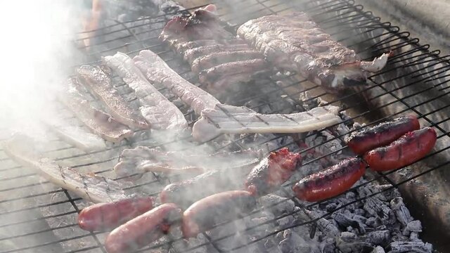 Barbacoa con panceta, chorizo y costillas sobre una parrilla con fuego debajo. 