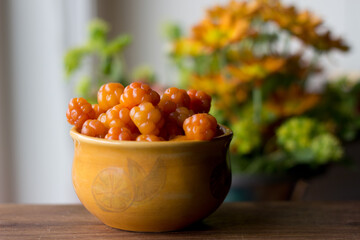 Cloudberry Rubus chamaemorus close up in orange bowl on wooden table,autumn harvest in norwegian mountains near Hemsedal ski resort,Buskerud,Norway,photo for printing on calendar,poster,wallpaper