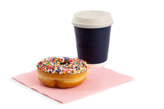 A Doughnut With Sprinkles And A Paper Take Out Coffee Cup On A Pink Napkin Isolated On White