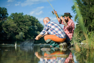 Big game fishing. Summer weekend. Two fishermen relaxing together with beer while fishing on lake at morning. Master baiter. Weekends made for fishing. Fly fish hobby of men. Make with inspiration.