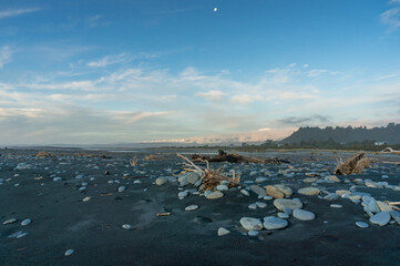 Beach landscape with black volcanic sand and pebbles, rocks