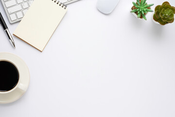Workspace in office with white table. Top view from above of keyboard with notebook and coffee. Desk for modern creative work of designer. Flat lay with blank copy space. Business and finance concept.