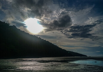 PAISAJE NATURAL OSCURO EN PLAYA CON EL SOL AL FONDO