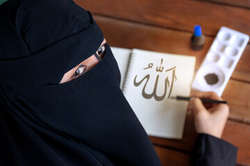 Arab Muslim woman writing Arabic handwriting with ink, Arabic letters mean the name of god 
