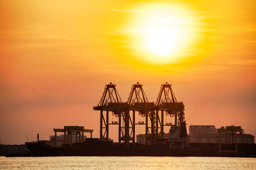Fototapeta na wymiar Crane for shipping container carrier with sunrise background 