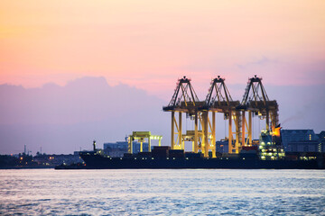 Crane for shipping container carrier with sunrise background
