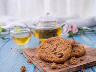 Tasty chocolate chip cookies stacked on a board served with tea and teapot on blue wooden table.Organic homemade snacks for healthy breakfast.Space for text and copy space