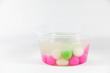 Colorful glutinous rice ball in a transparent plastic container in a white isolated background