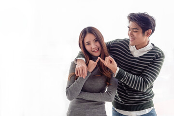 Asian male and female couples wear long - sleeve sweaters, organize a New Year's party at home together.Handsome young man trying to reconcile with his girlfriend after the argument.