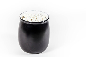 white powder in a black pot in a white isolated background