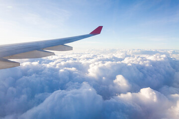 Fototapeta premium Plane wing view from inside plane in midair with blue sky cloud background