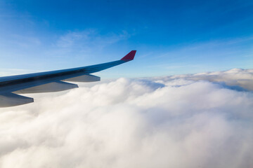 Plane wing view from inside plane in midair with blue sky cloud background