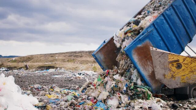 Dump truck unloading waste on landfill, environmental concept.